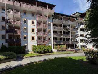 Discover this charming apartment building featuring multiple balconies with intricate wooden railings, perfect for enjoying mountain views.