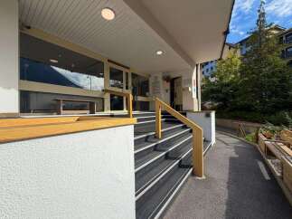 Discover this inviting property featuring a welcoming entrance with a sturdy wooden handrail guiding you up a set of carpeted stairs.