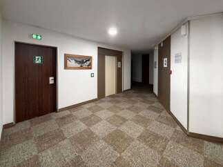 Discover this inviting hallway featuring a patterned carpet and a prominent exit sign on a dark wooden door.