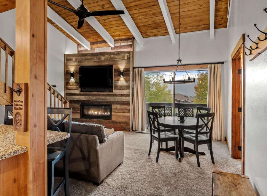 Experience rustic charm in this inviting living and dining area, featuring a striking wood-paneled accent wall with a modern fireplace and mounted television.