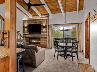 Experience rustic charm in this inviting living and dining area, featuring a striking wood-paneled accent wall with a modern fireplace and mounted television.