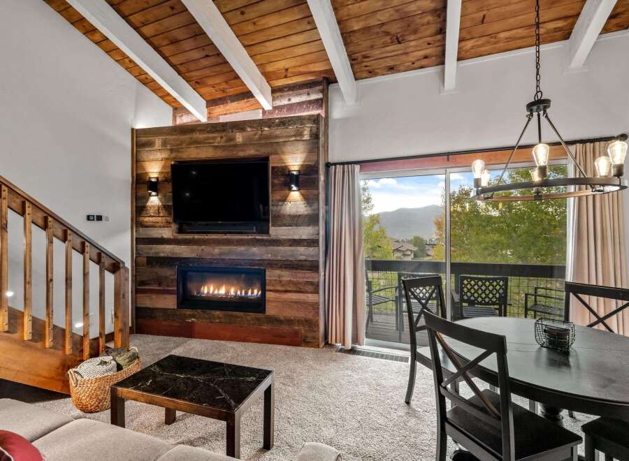 Experience cozy living with this inviting living room featuring a rustic wood-paneled fireplace and a large flat-screen TV.