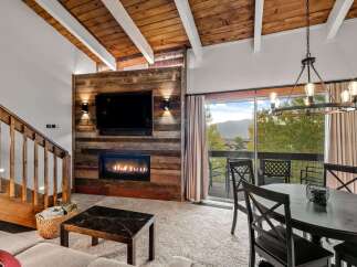 Experience cozy living with this inviting living room featuring a rustic wood-paneled fireplace and a large flat-screen TV.