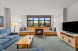 Cozy up by the fireplace in this inviting living room, featuring a built-in wooden bench seating area perfect for enjoying the scenic views through the large window.
