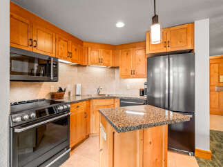 This charming kitchen boasts beautiful light wood cabinetry complemented by granite countertops and a tiled backsplash.