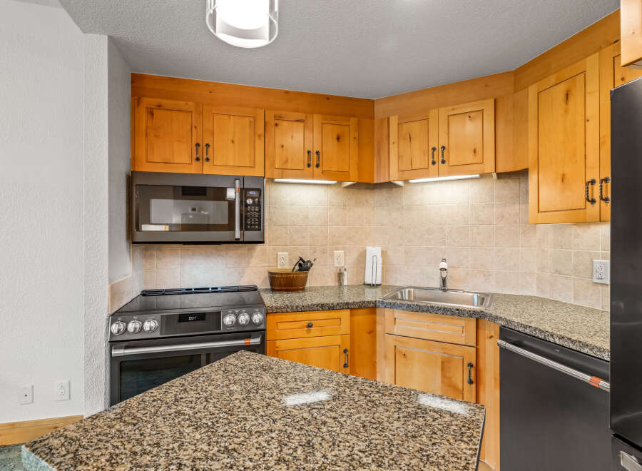 This charming kitchen features warm, natural wood cabinetry complemented by a speckled granite countertop.
