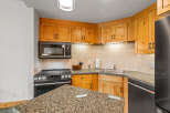 This charming kitchen features warm, natural wood cabinetry complemented by a speckled granite countertop.