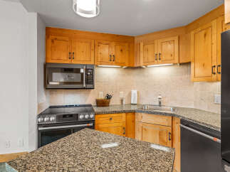 This charming kitchen features warm, natural wood cabinetry complemented by a speckled granite countertop.
