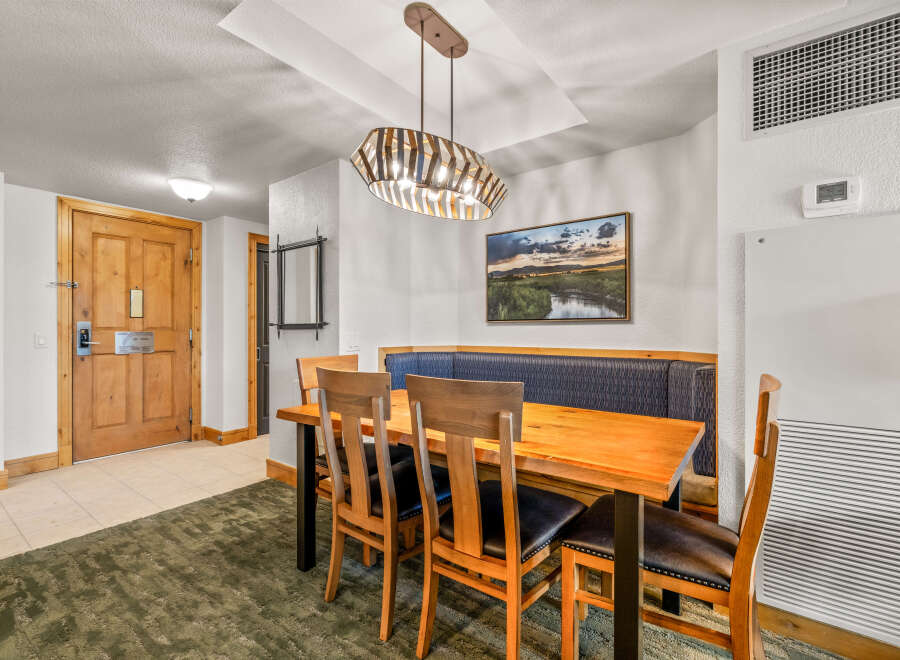 Enjoy meals in this inviting dining area featuring a rustic wooden table with comfortable upholstered chairs and a built-in banquette.