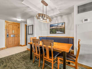 Enjoy meals in this inviting dining area featuring a rustic wooden table with comfortable upholstered chairs and a built-in banquette.
