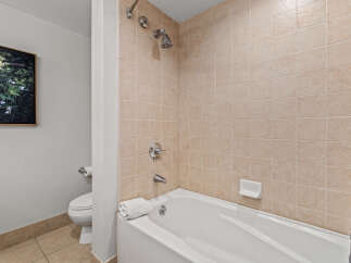 This bathroom features a clean and functional design with a white bathtub and shower combination, complemented by neutral-toned tiled walls.