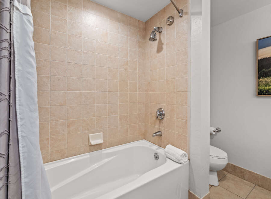 This bathroom features a classic tiled shower and tub combination, perfect for a relaxing soak.
