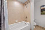 This bathroom features a classic tiled shower and tub combination, perfect for a relaxing soak.