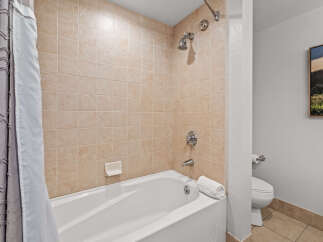 This bathroom features a classic tiled shower and tub combination, perfect for a relaxing soak.