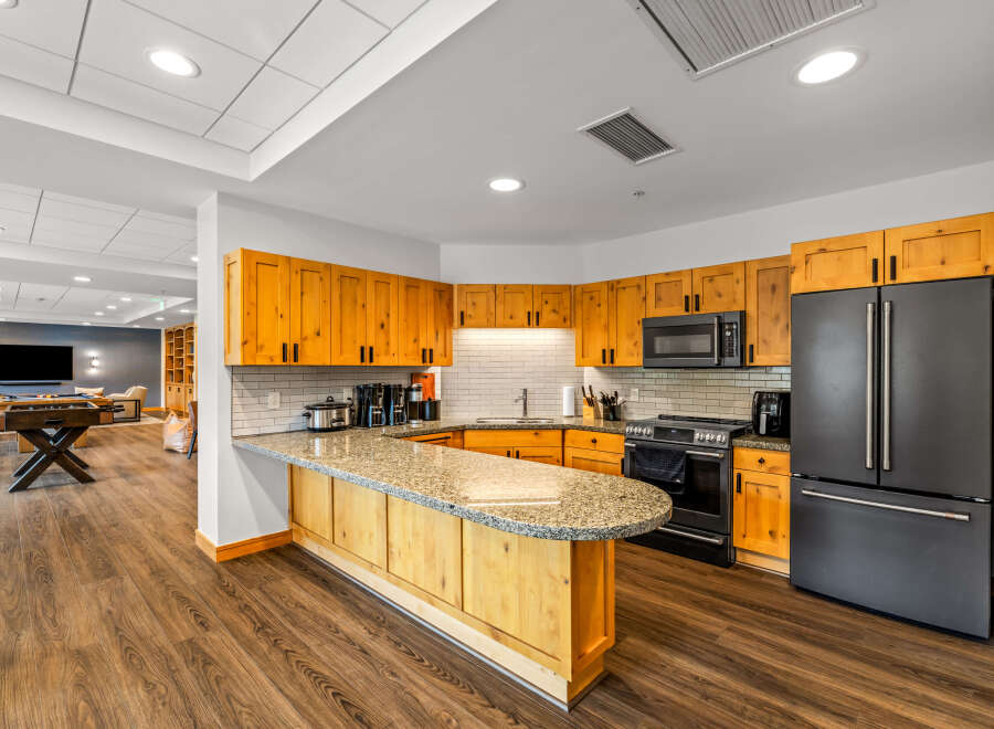 Discover this modern kitchen featuring warm wood cabinetry and a sleek granite countertop island, perfect for casual dining or entertaining.