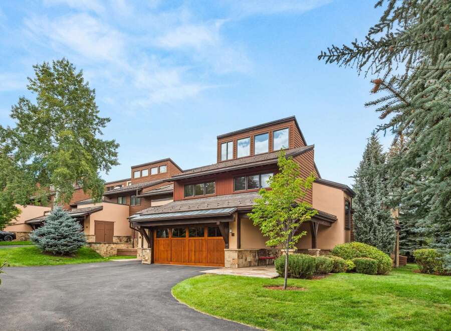 Discover this stunning mountain home featuring a warm, natural wood garage door and a charming stone facade.