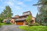 Discover this stunning mountain home featuring a warm, natural wood garage door and a charming stone facade.