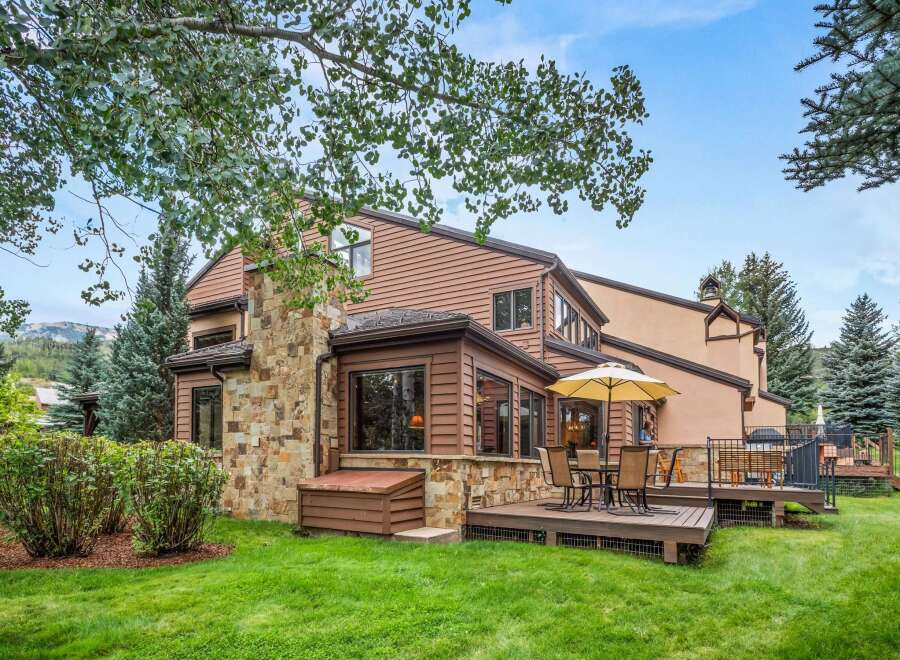 Enjoy outdoor living with this charming home featuring a spacious deck and a large umbrella for shaded relaxation.