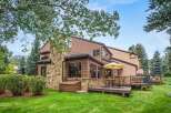 Enjoy outdoor living with this charming home featuring a spacious deck and a large umbrella for shaded relaxation.