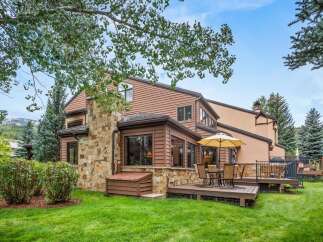 Enjoy outdoor living with this charming home featuring a spacious deck and a large umbrella for shaded relaxation.