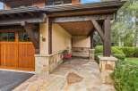 Experience rustic charm with this inviting covered entryway, featuring exposed wooden beams and a natural stone facade.