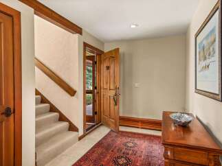 Step into this inviting entryway featuring a warm wooden door and a plush oriental rug that leads to a carpeted staircase.