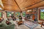 Experience rustic charm in this inviting living room, featuring a grand stone fireplace and a vaulted wood-paneled ceiling.