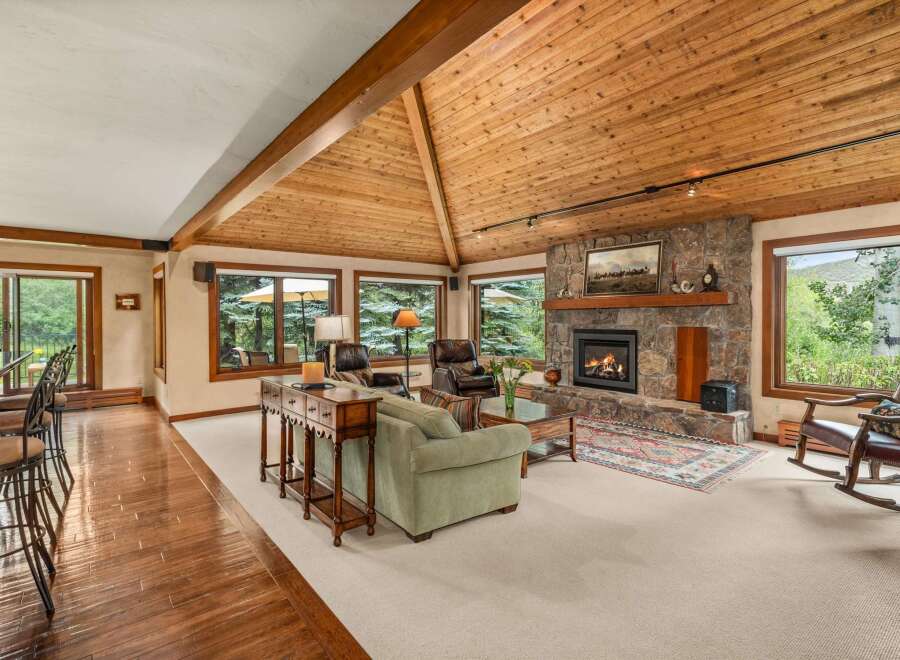 Experience rustic charm in this spacious living area, featuring a grand stone fireplace and a vaulted, wood-paneled ceiling.