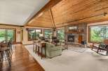Experience rustic charm in this spacious living area, featuring a grand stone fireplace and a vaulted, wood-paneled ceiling.
