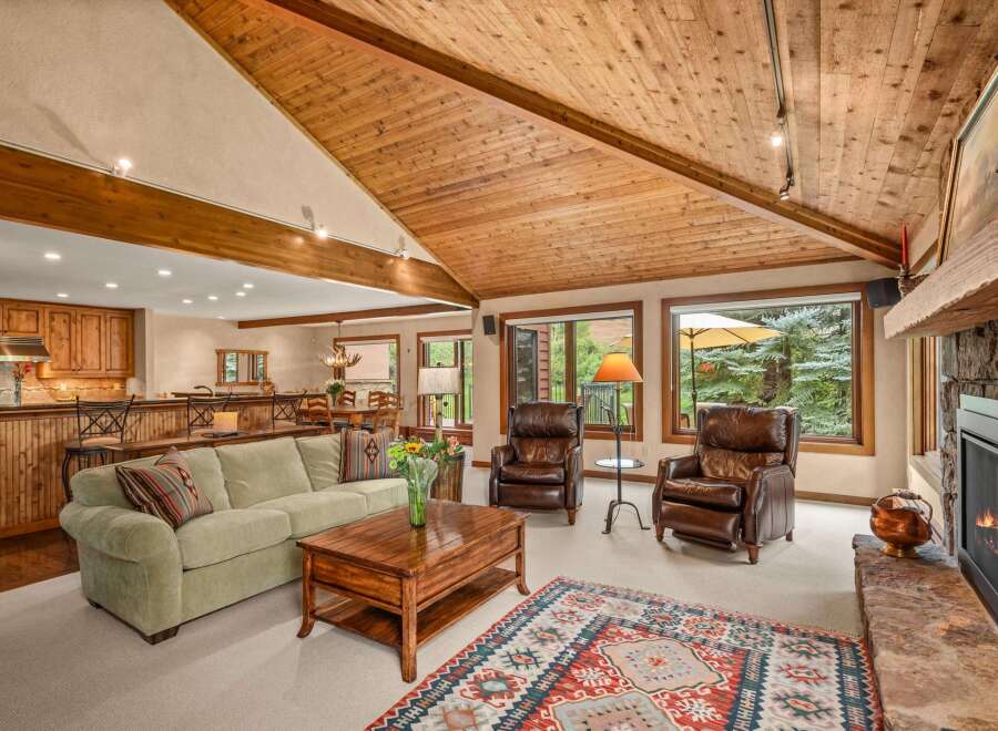 Experience rustic charm and modern comfort in this inviting living space, featuring a vaulted wood-paneled ceiling and a cozy stone fireplace.