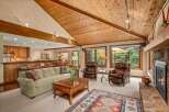 Experience rustic charm and modern comfort in this inviting living space, featuring a vaulted wood-paneled ceiling and a cozy stone fireplace.