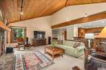 Experience rustic charm in this spacious living area featuring a vaulted wood-paneled ceiling and a cozy stone fireplace.
