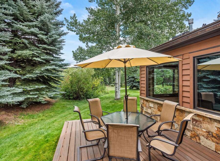 Enjoy outdoor living on this charming deck, complete with a glass-top dining table and comfortable seating, perfect for al fresco meals.