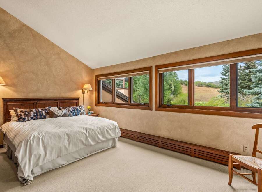 Experience serene mountain living in this charming bedroom, featuring a plush king-size bed adorned with decorative pillows and a cozy duvet.