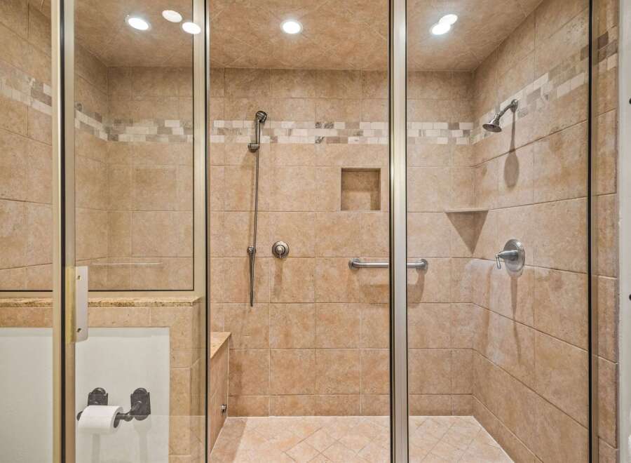 Step into this luxurious walk-in shower, featuring elegant tiled walls and a built-in bench for ultimate comfort.