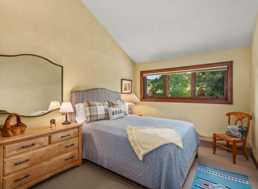 This charming bedroom features a comfortable queen-size bed with a plush quilted coverlet and decorative pillows.