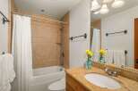 This charming bathroom features a tiled shower and tub combination, complemented by a granite-topped vanity with a modern sink and faucet.