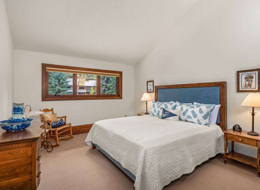 Experience cozy mountain living in this charming bedroom, featuring a plush king-size bed adorned with decorative pillows and a white quilted comforter.