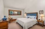 Experience cozy mountain living in this charming bedroom, featuring a plush king-size bed adorned with decorative pillows and a white quilted comforter.