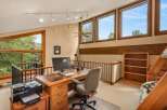 This spacious loft office features a large wooden desk with a computer, printer, and ample storage, perfect for a home workspace.
