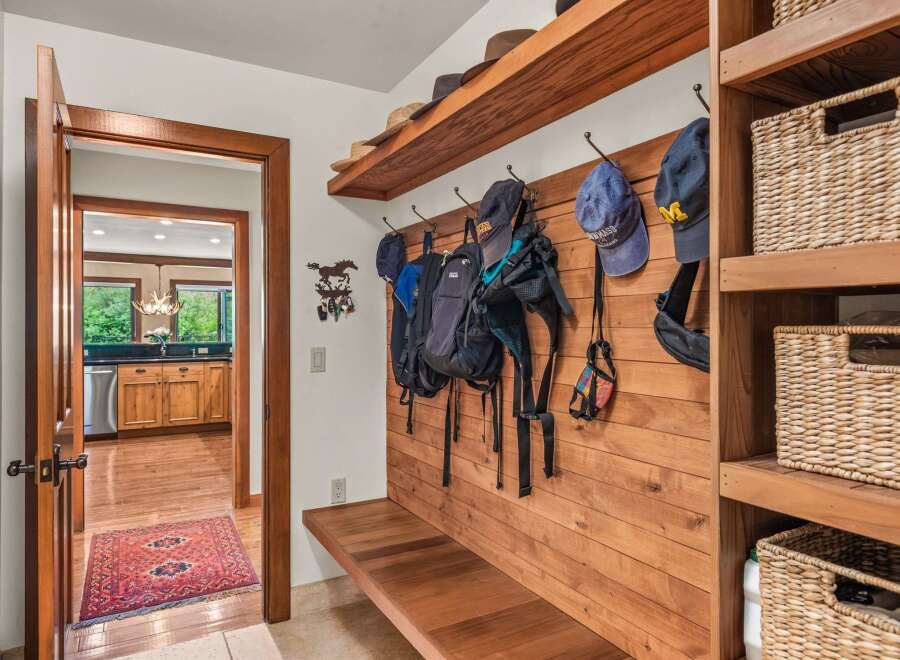 This charming entryway features a rustic wooden bench with hooks for coats and bags, perfect for a mudroom or foyer.