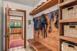 This charming entryway features a rustic wooden bench with hooks for coats and bags, perfect for a mudroom or foyer.