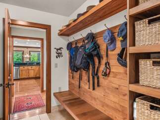 This charming entryway features a rustic wooden bench with hooks for coats and bags, perfect for a mudroom or foyer.