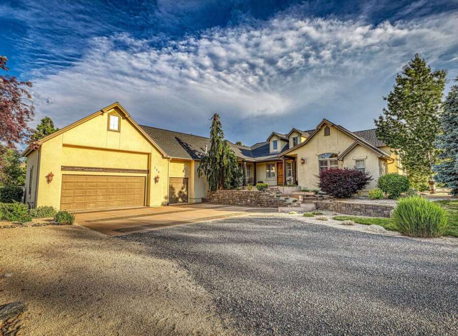 This stunning home boasts a welcoming facade with a large driveway leading to a spacious three-car garage.