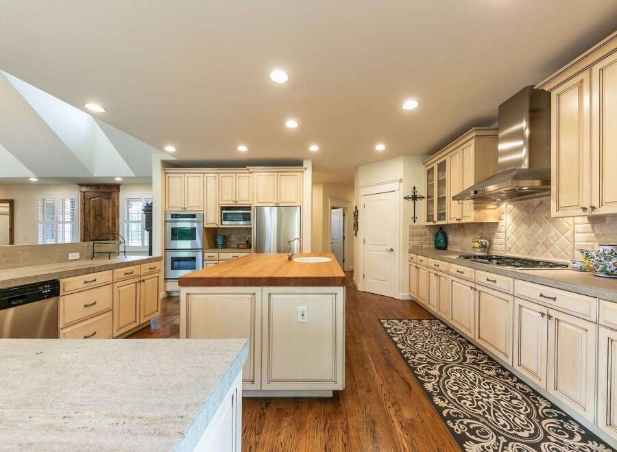 This spacious kitchen boasts a large butcher block island with a sink, perfect for meal preparation and casual dining.