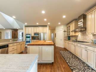 This spacious kitchen boasts a large butcher block island with a sink, perfect for meal preparation and casual dining.