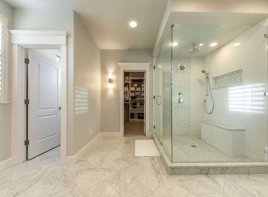 Experience luxury in this master bathroom featuring a spacious walk-in shower with a built-in bench and intricate tile accents.
