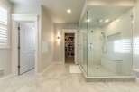 Experience luxury in this master bathroom featuring a spacious walk-in shower with a built-in bench and intricate tile accents.