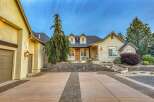 Discover this stunning stucco home featuring a welcoming driveway with decorative brick accents and a charming stone retaining wall.