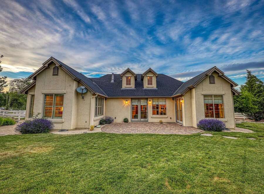 This stunning home features a beautifully manicured lawn and a charming patio area, perfect for outdoor entertaining.